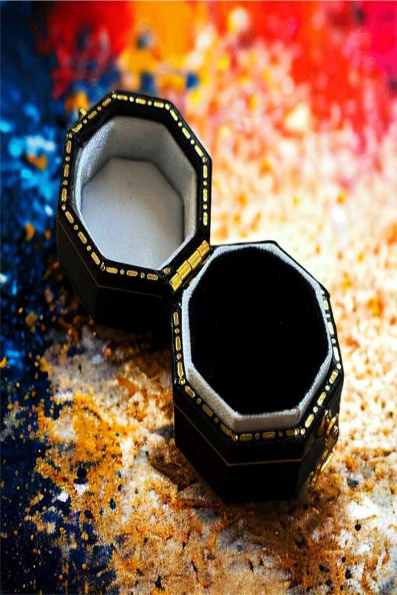 Black jewelry box with gold accents on a colorful abstract background